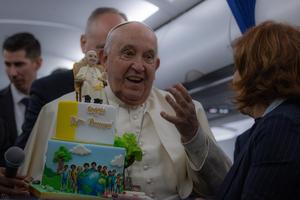 Pope Francis holds a gift on the papal plane coming back from Corsica on Dec. 15, 2024. He celebrates his 88th birthday today.