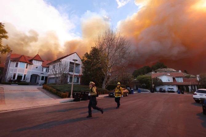 Firefighters run as a brush fire burns in Pacific Palisades, California, on Jan. 7, 2025. A fast-moving brushfire in a Los Angeles suburb burned buildings and sparked evacuations as “life-threatening” winds whipped the region. Firefighters run as a brush fire burns in Pacific Palisades, California, on Jan. 7, 2025. A fast-moving brushfire in a Los Angeles suburb burned buildings and sparked evacuations as “life-threatening” winds whipped the region.