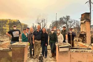 Jacqueline Halpin and her family gather at the burned family home, with their Marian statue in the foreground.