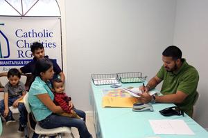 A volunteer at a Catholic Charities Humanitarian Respite Center helps a Central American refugee family. 