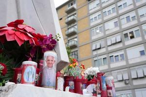 Candles are set at the feet of a statue of Pope John Paul II on Feb. 20, 2025, outside Gemelli Hospital in Rome, where Pope Francis is hospitalized for tests and treatment for bronchitis. 