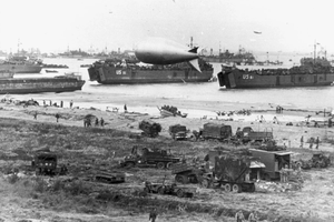U.S. Navy LSTs and other vessels unloading at low tide at Normandy, soon after the June 1944 invasion. USS LST-55 is in the center, behind the closest barrage balloon. USS LST-61 is at right.
