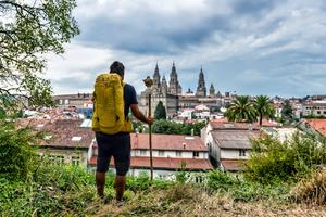 A pilgrim approaches the end of the Camino de Santiago as he catches sight of the Basilica of St. James in the distance in Galicia, Spain.