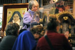 A portrait of St. Thérèse is seen as people surround a case containing her relics at St. Teresa of Lisieux Church in Taunton, west England, on Sept. 18, 2009.  Thérèse was declared a saint in 1925. Taunton is a sister city of Lisieux, France, the hometown of Thérèse. 