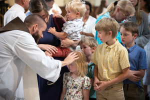 Capuchin Father Michael Herlihey, one of three chaplains serving pilgrims along the Drexel Route, blesses children following the opening Mass of the 2025 Eucharistic Pilgrimage in Indianpolis on May 18, 2025.