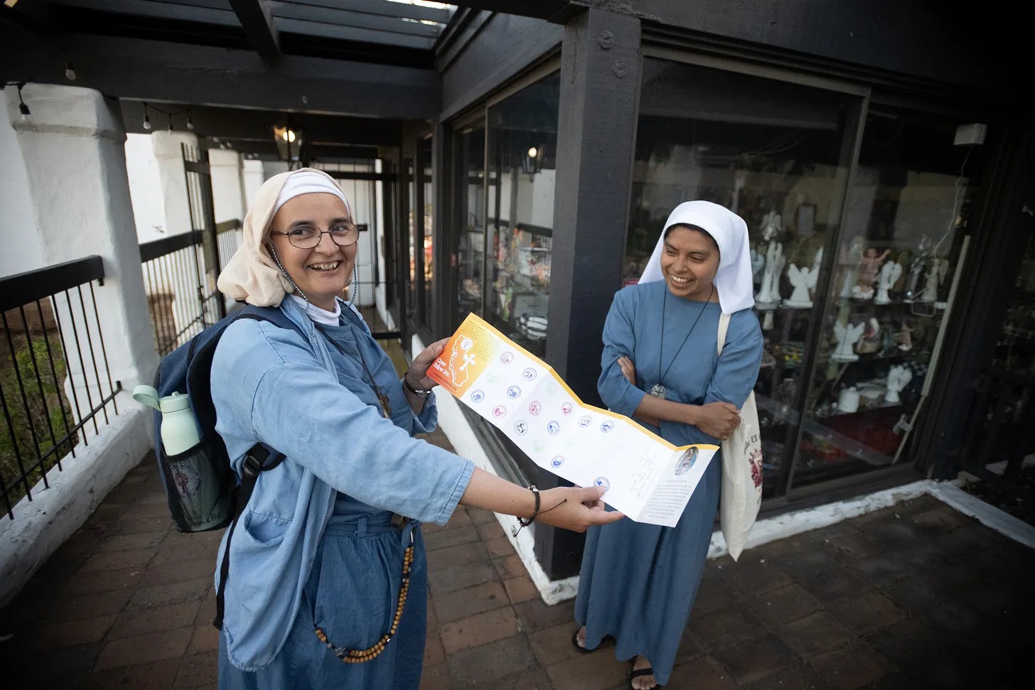 Sister Armelle and her companion from the Camino de California pilgrimage show her stamped pilgrimage passport outside Mission San Diego de Alcalá.