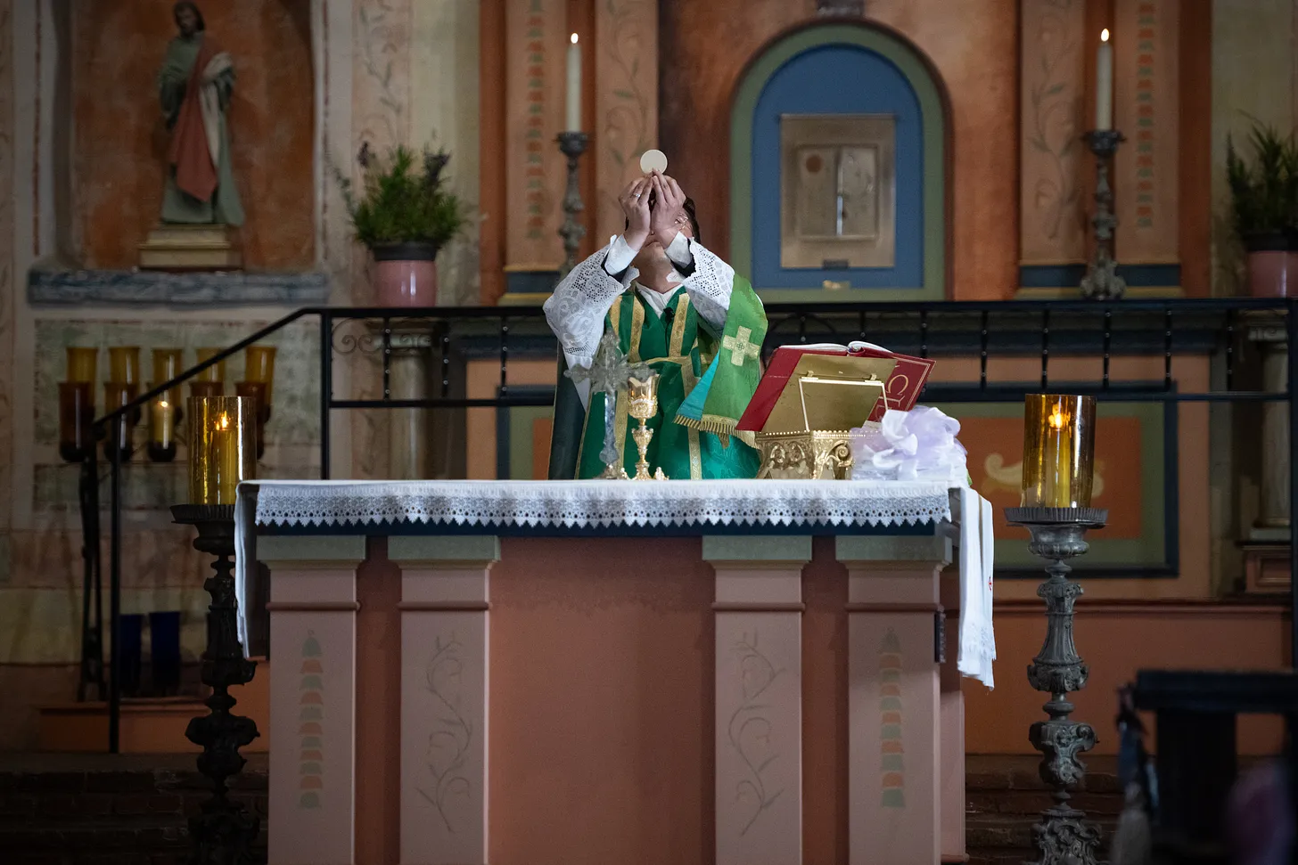 The priest elevates the host during the consecration at Mission San Diego de Alcalá—a Eucharistic moment echoing centuries of Faith.