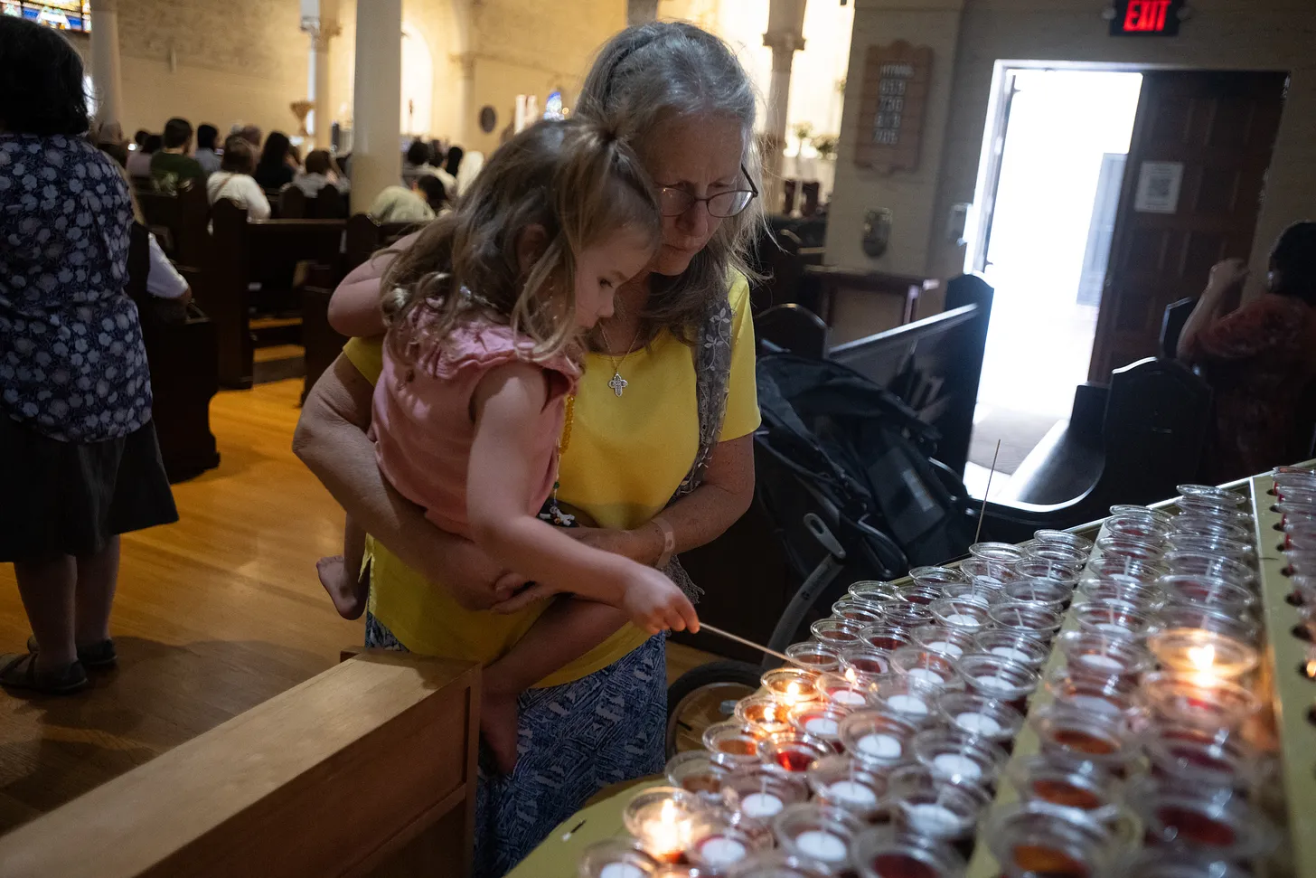 A mother helps her daughter light a candle inside Our Lady of the Rosary Church, one of the final stops of the Camino de California procession.
