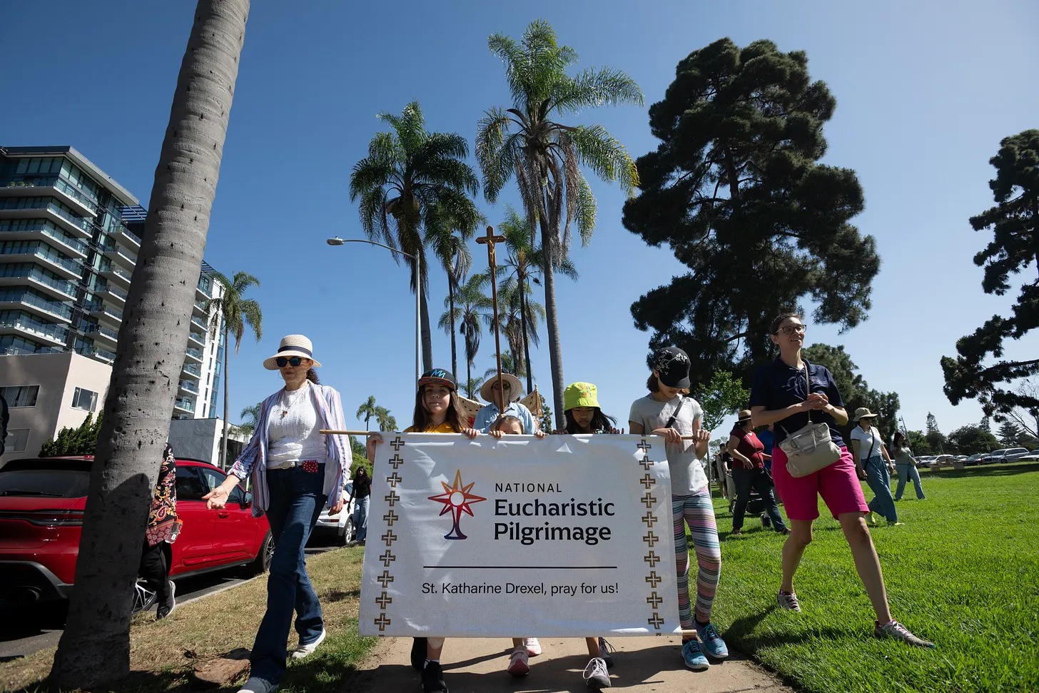 Children carry the National Eucharistic Pilgrimage banner through Balboa Park in San Diego, invoking the intercession of St. Katharine Drexel as pilgrims journey with Christ.