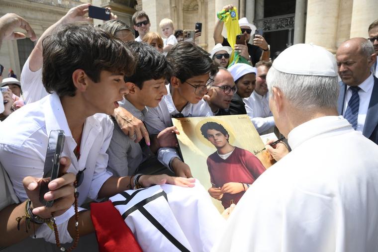 Young people have Pope Leo XIV sign a painting of the future saint Carlo Acutis at the end of the June 18, 2025, general audience. 