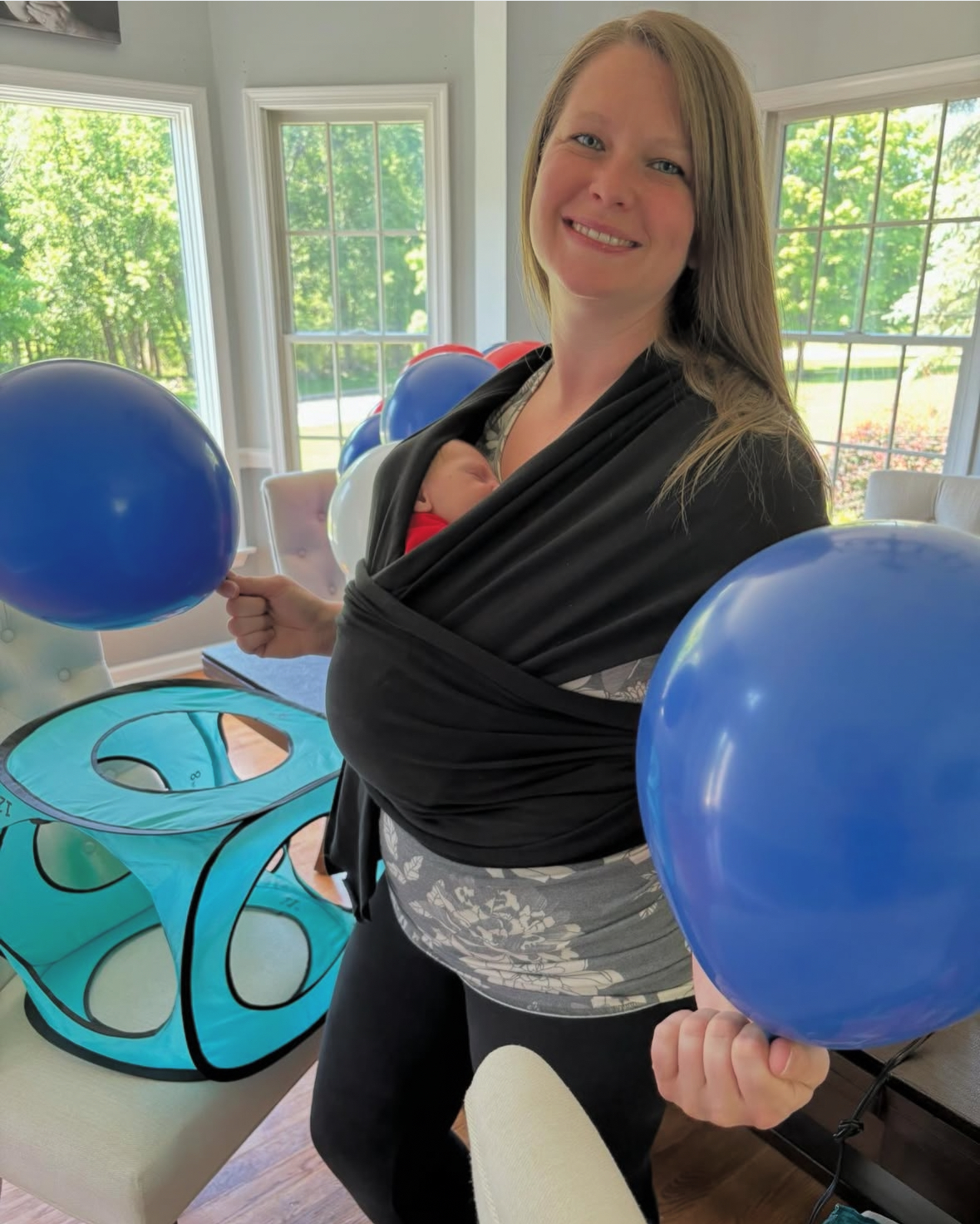 Daniella Delaney working away on a 25 foot arch for a local 5K in 2024 along with her sleeping newborn just 3 weeks old.