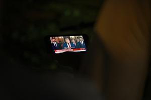 People watch U.S. President Donald Trump address the nation from the White House in Washington, on June 21, 2025, following the announcement that the U.S. bombed nuclear sites in Iran, from Lafayette Square outside the White House. 