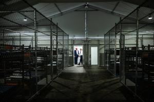 Rows of bunk beds line the interior of the so-called “Alligator Alcatraz” detention facility in the Florida Everglades, a repurposed training center now designated for holding immigrants. President Donald Trump appears in the background during a July 1, 2025 visit to the site, which has drawn criticism from Bishop Frank Dewane and other Catholic leaders.