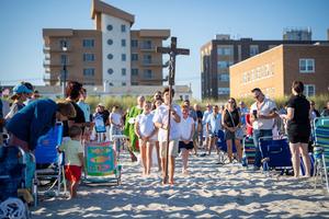 A processional cross made from the wood left over from the Long Island boardwalk destroyed by Hurricane Sandy in 2012  is carried across the sand  ahead of Sunday Mass as part of the Beach Catholic initiative on Long Island on July 6, 2025.