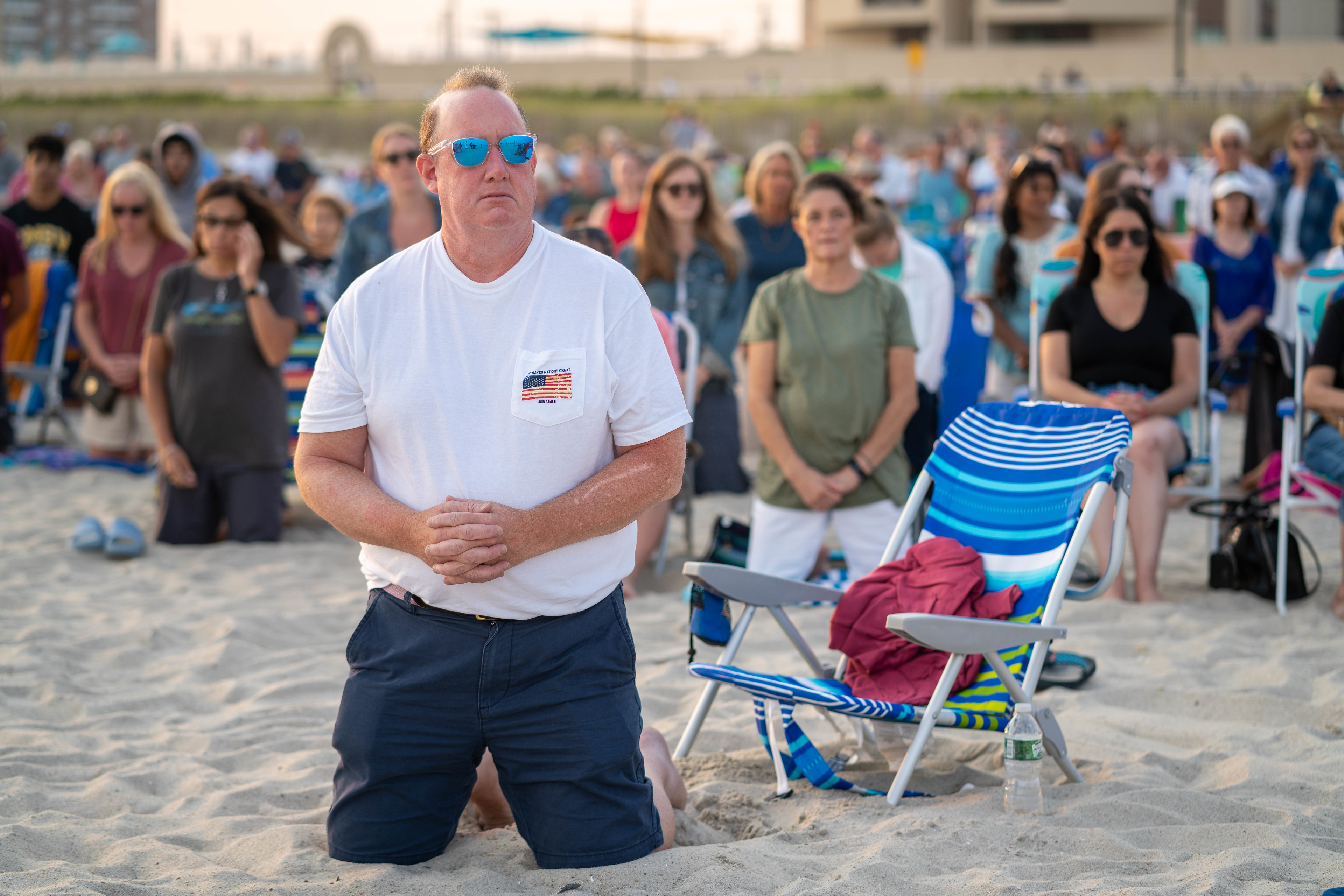 Fiéis ajoelhados na areia durante a Missa na praia