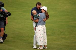 U.S. golfer Scottie Scheffler celebrates with his wife Meredith and son Bennett on the 18th green after his victory in the 153rd Open Championship at Royal Portrush golf club in Northern Ireland on July 20, 2025.  