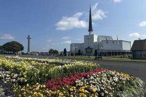 Flowers stand before Knock Shrine in Knock, Ireland, Friday, Aug. 15, 2025 