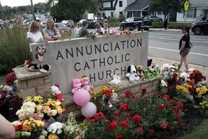 People leave flowers and other mementoes in front of Annunciation Catholic Church on Thursday; the memorial to the victims of Wednesday’s shooting in Minneapolis is rapidly growing.