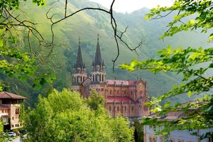 The Basílica de Santa María la Real de Covadonga rises through the trees in the hills of Cangas de Onís, marking the site where Christian resistance against Islamic rule began in Spain.