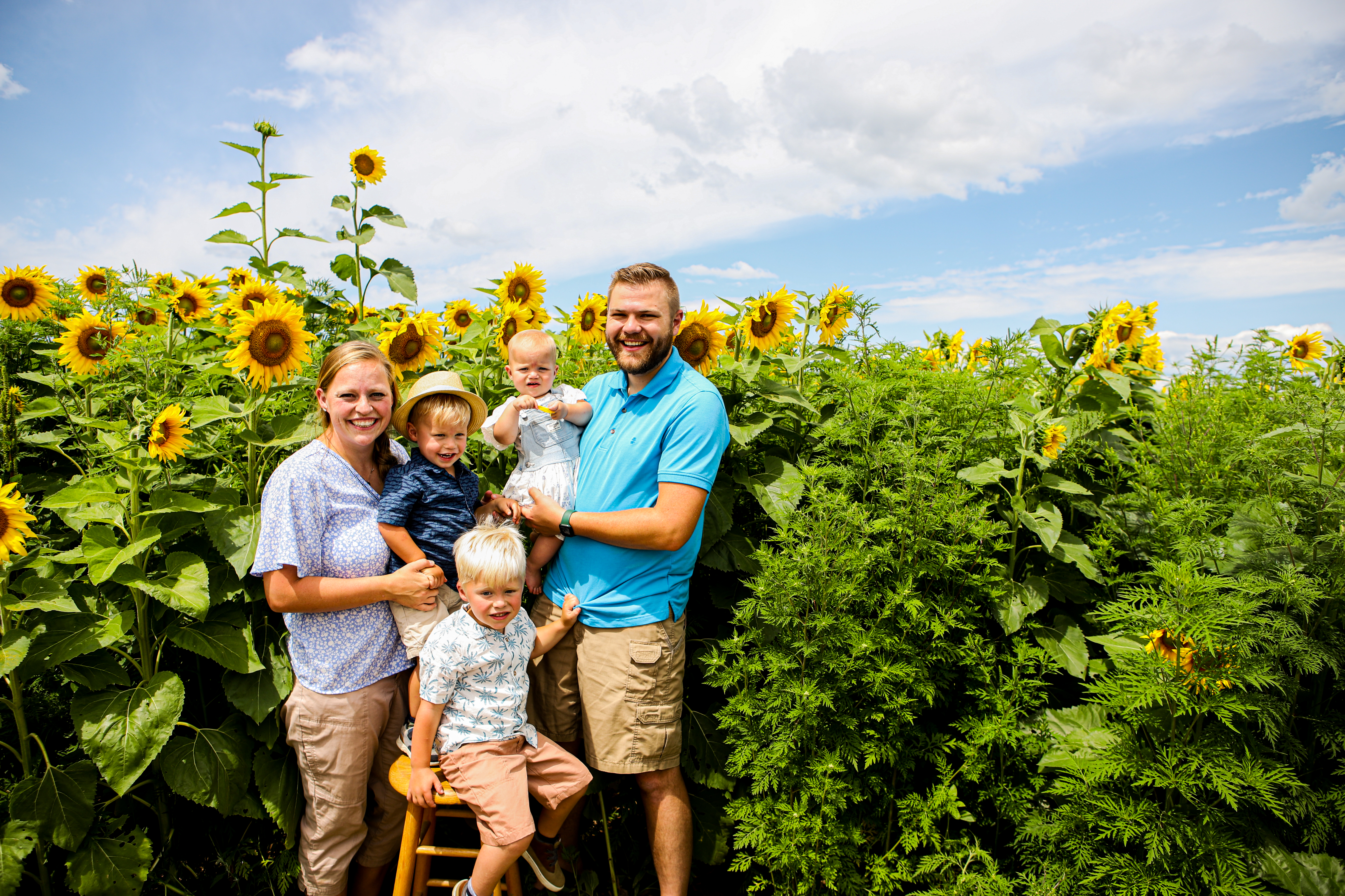 Emma and Isaac Follett snap a family photo in front of sunflowers. 