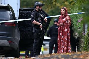 An armed police officer talks to a member of the local community outside Heaton Park Hebrew Congregation synagogue in Crumpsall, north Manchester, England, on Thursday, Oct. 2, 2025.