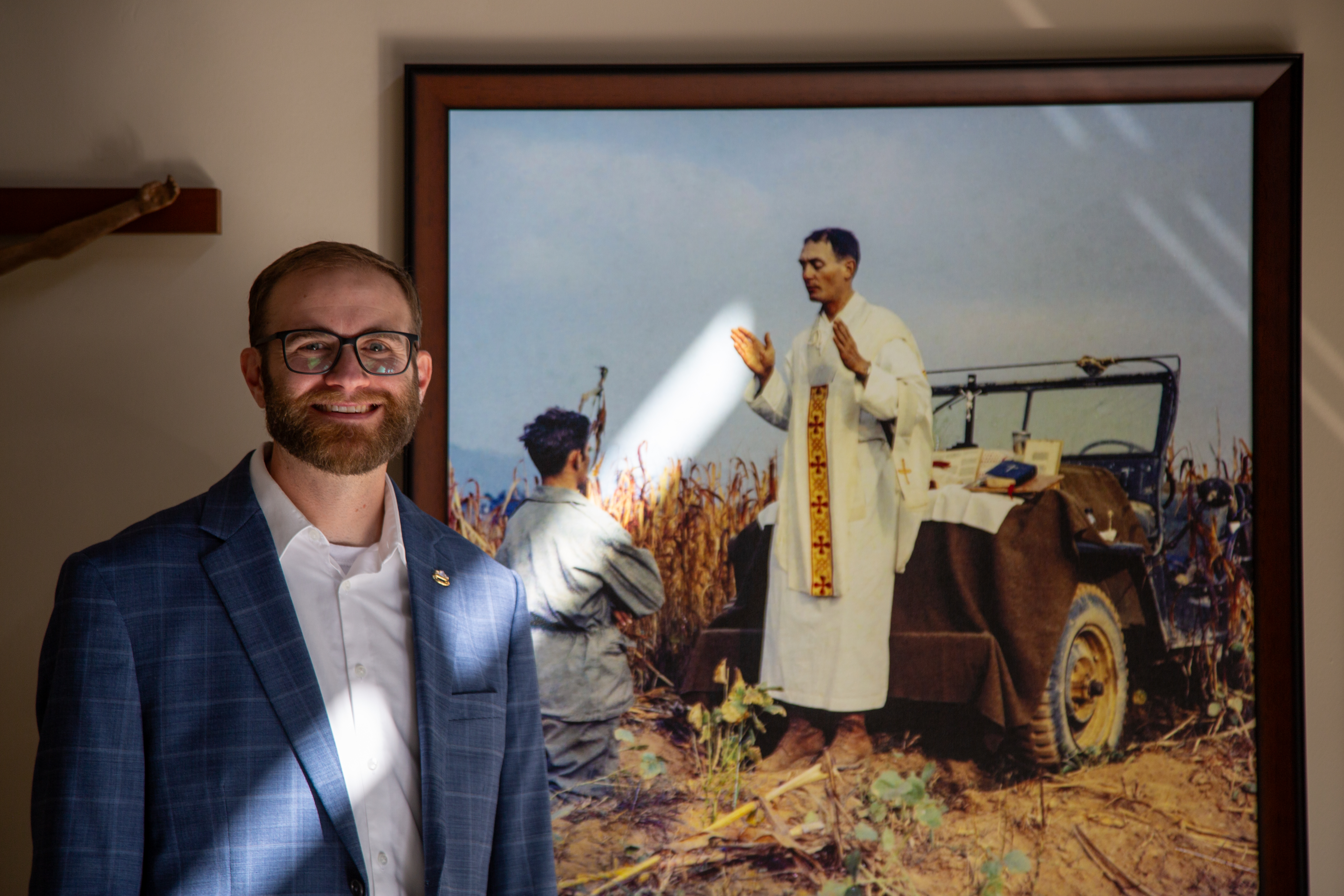 Scott Carter, coordinator of the Father Kapaun Guild in Wichita, with a framed "Jeep Mass" photo at the diocesan headquarters