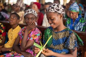 A teenage girl makes a cross with a palm during the Palm Sunday Mass at Christ the King Catholic Church in Ibadan, Oyo, Nigeria, on March 24, 2024.