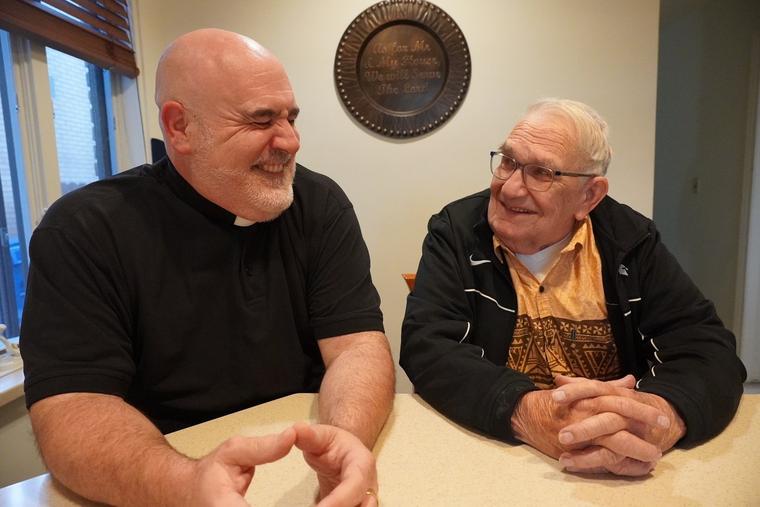 L to R: Father Joe Krupp laughs as his father, Gordon Krupp, smiles in their shared rectory residence.                           