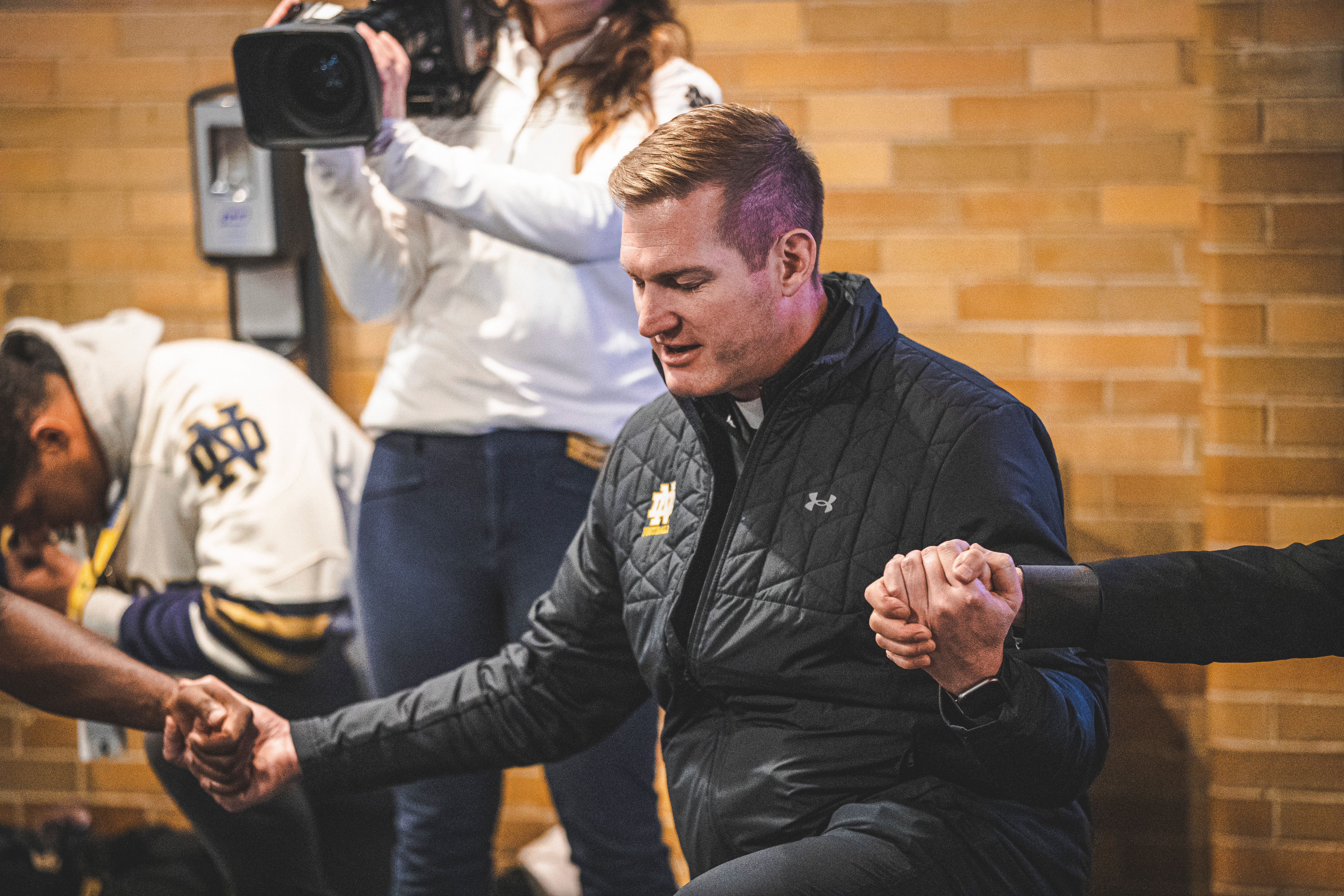 Holy Cross Father Nate Wills prays with the team.
