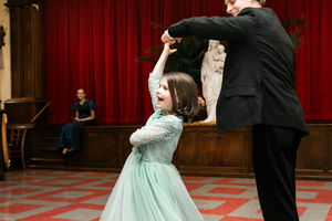 A young daughter enjoys dancing with her dad.