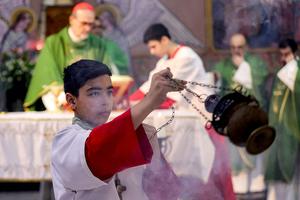 A young altar server censes as Cardinal Pierbattista Pizzaballa, Latin Patriarch of Jerusalem, prepares the eucharist during Sunday morning Mass at the Roman Catholic Church of the Holy Family in Gaza City on July 20, 2025.          