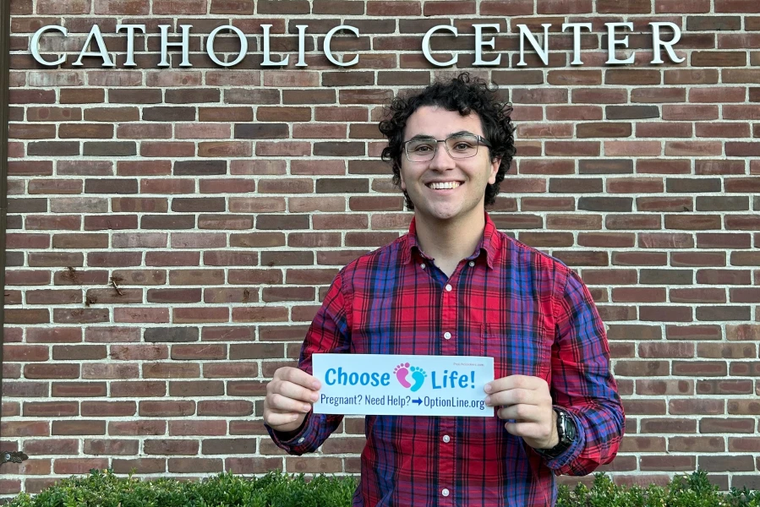 Gabriel Dionisi, a 22-year-old college student who makes pro-life bumper stickers with the goal of spreading the pro-life message and spread awareness to others, displays one of his works.