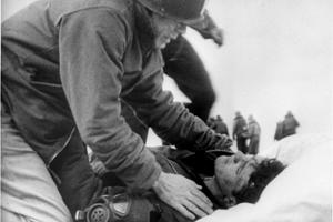 A Catholic chaplain, Lieutenant Commander Joseph T. O'Callahan, administering the last rites to an injured crewman aboard USS Franklin, after the ship was set afire by a Japanese air attack on March 19, 1945.