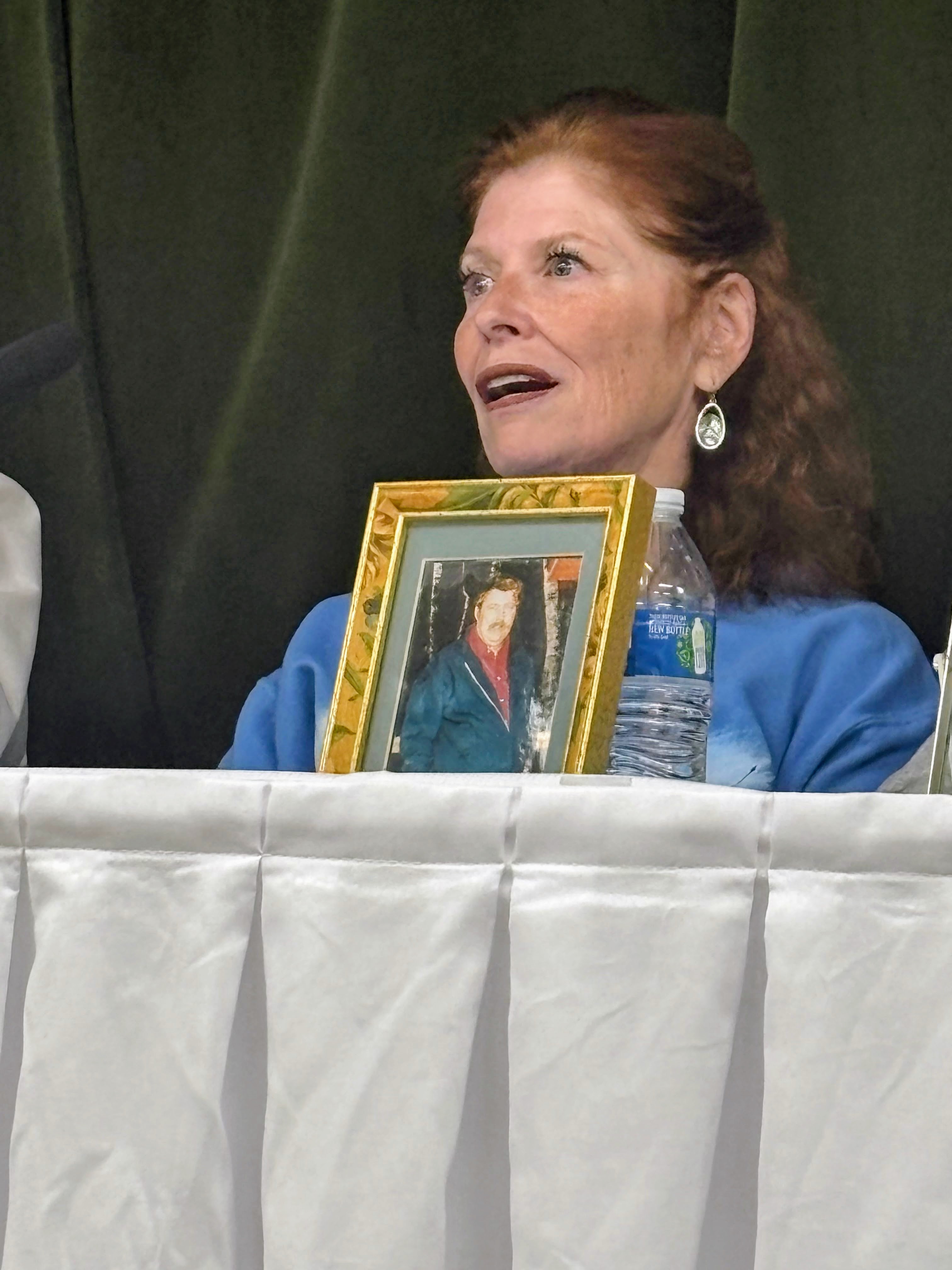 Debbie Gomez-Felder holds a picture of her father, Oliver “Buck” Champeau.