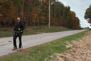 Father Gary Graf walks down a rural road during his trek across America in support of immigrants on Friday, Oct. 17, 2025.