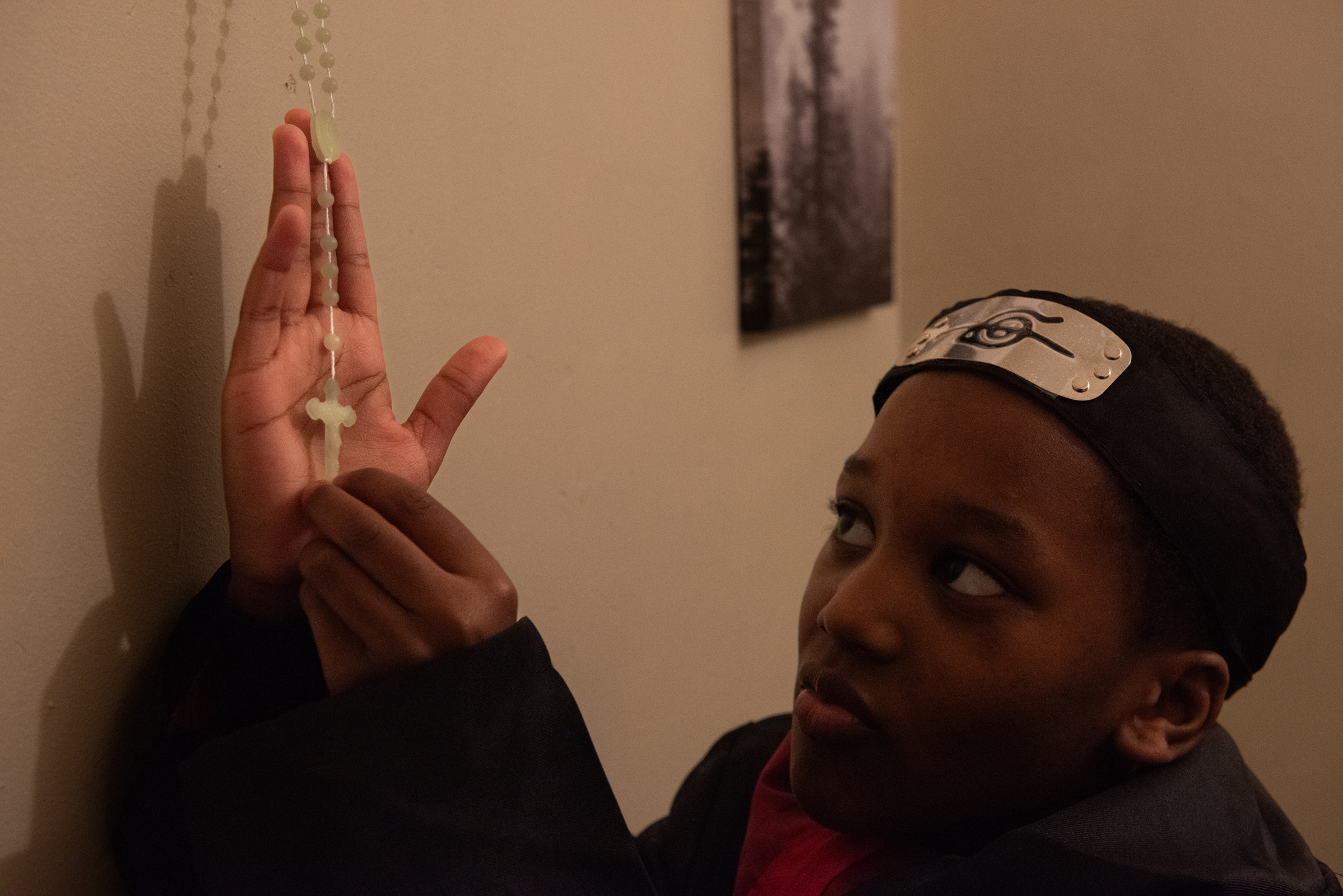 A boy shows off his rosary that he hangs on display in his house. 
