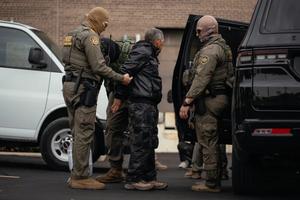 A person detained is taken to a parking lot on the far north side of the city before being transferred to an Immigration and Customs Enforcement facility in Chicago on Oct. 31, 2025.