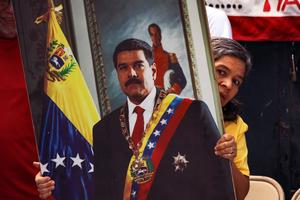A woman holds a portrait of Nicolás Maduro at a rally in San Salvador, El Salvador, following the announcement that he had been captured in Caracas after a U.S.-led military operation.