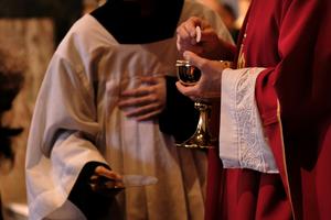 A priest distributes Communion at Mass.