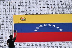 A man takes a picture of portraits of political prisoners during a demonstration by relatives at the Central University of Venezuela in Caracas on Jan. 13.