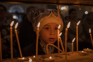 A boy looks at the burning candles during the Catholic Easter celebration at the Cathedral of St. Oleksandr on April 9, 2023, in Kyiv, Ukraine.