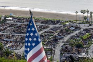 An American flag stands on a cliff overlooking the remains of the Pacific Palisades Bowl Mobile Estates, which was destroyed in the 2025 Palisades fire, on the one-year anniversary in Pacific Palisades, California.  