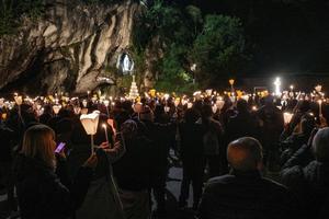 Pilgrims hold candles during Mass Nov. 1, 2024, at Lourdes.