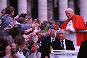 Pope John Paul II greeting the crowd from his popemobile; in front of him, Angelo Gugel, his papal assistant in Vatican Square. 