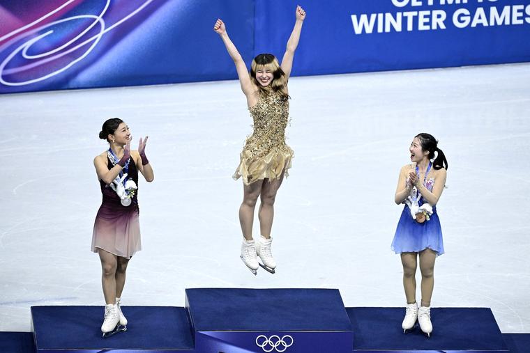 Gold medalist Alysa Liu (center) celebrates on the podium with silver medalist Kaori Sakamoto of Japan (left) and bronze medalist Ami Nakai of Japan after the women’s singles free skate at the 2026 Milano Cortina Winter Olympics at the Milano Ice Skating Arena in Milan Feb. 19, 2026.