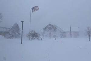 Snow-covered Corpus Christi Church in Sandwich, Massachusetts, in the early morning of Feb. 23, 2026, as an American flag flies in the blizzard conditions.