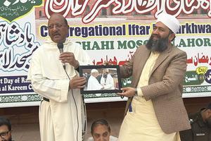Dominican Father James Channan presents a framed photo of Abdul Khabeer Azad, the Badshahi Mosque’s prayer leader, who met Pope Leo XIV in October 2025, at the mosque’s iftar in Lahore on Feb. 27, 2026. 