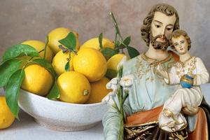 A statue of St. Joseph holding the infant Jesus is shown alongside a bowl of lemons, a symbol tied to a St. Joseph’s Day tradition associated with finding a spouse.