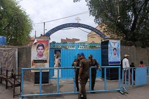 Pakistani police stand guard outside St. John's Catholic Church in Youhanabad, Lahore, on March 15, 2025. Posters of Servant of God Akash Bashir flank the entrance gate on the 10th anniversary of twin suicide bombings that struck the neighborhood.