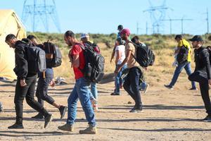 Migrants and asylum seekers head back to their tents in a makeshift camp after being turned away from Border Patrol agents who picked up only women, children, and families. The rest of the men were ferried away less than an hour later. 